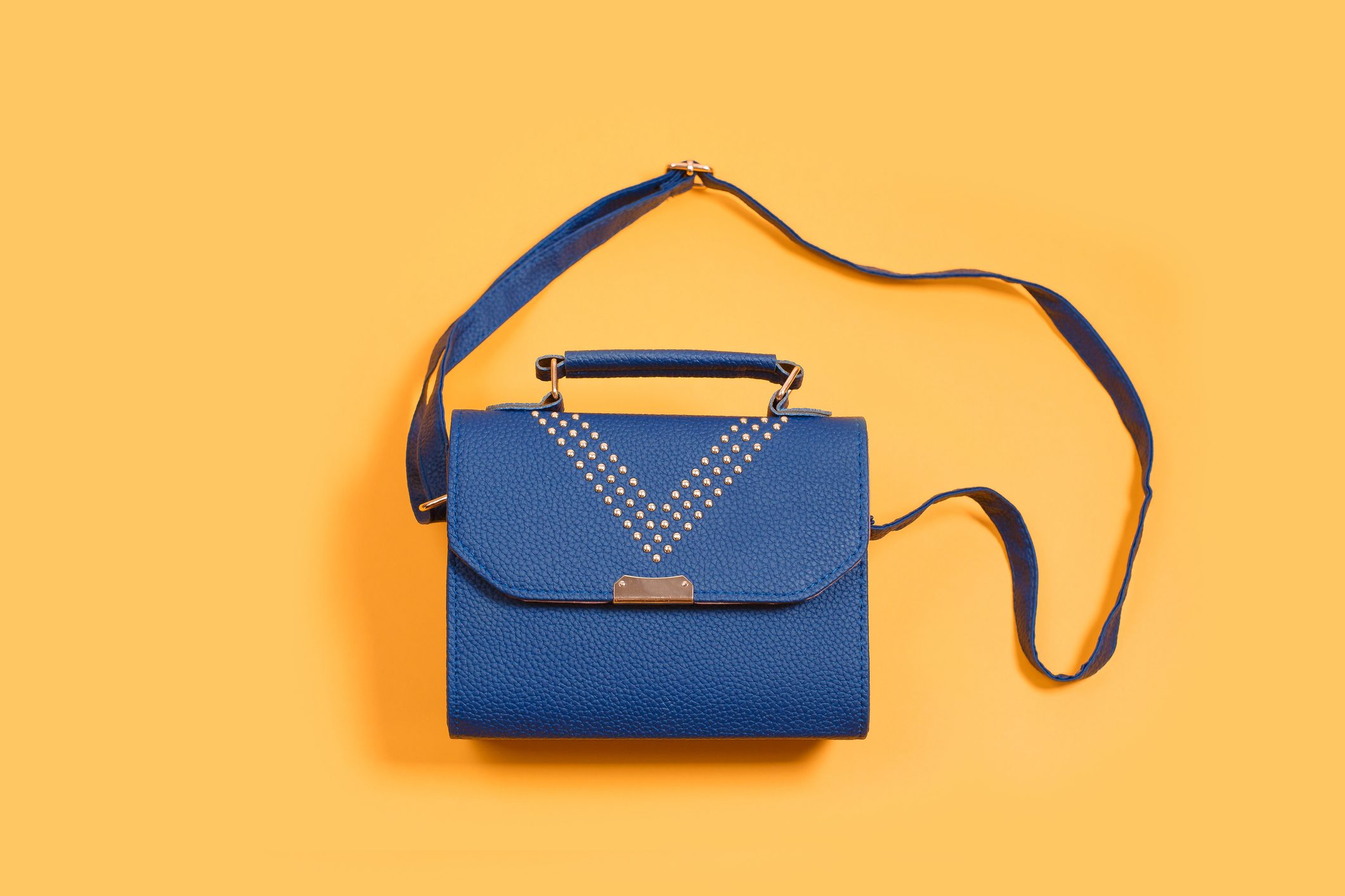 Woman leather small handbag clutch on yellow background.