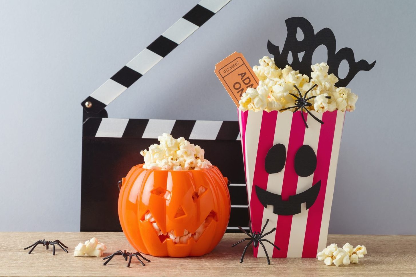 Horror movie night and Halloween party concept with jack o lantern pumpkin, popcorn and movie clapperboard on wooden table