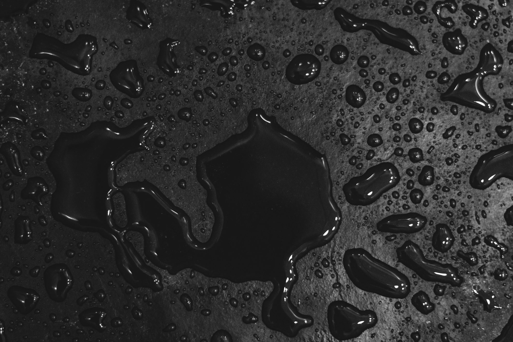 Water droplets scatter and glisten on a dark, textured surface.