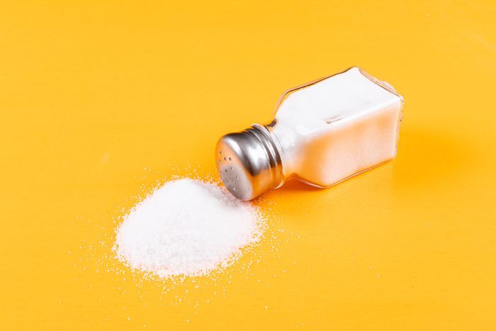 High angle view sea salt coming out of salt shaker on orange background horizontal,Romania
