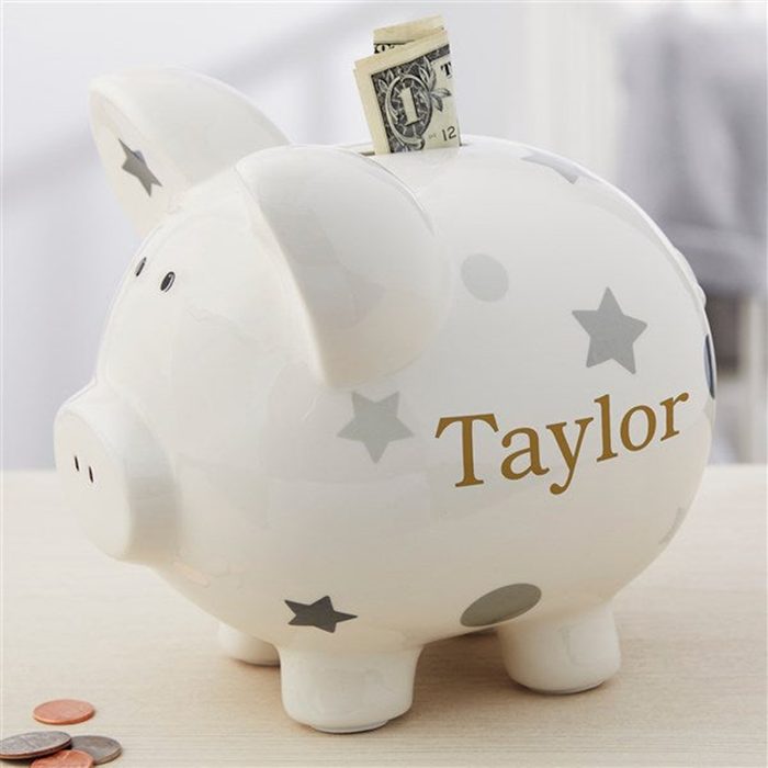Piggy bank holds a folded dollar bill, decorated with stars, labeled 