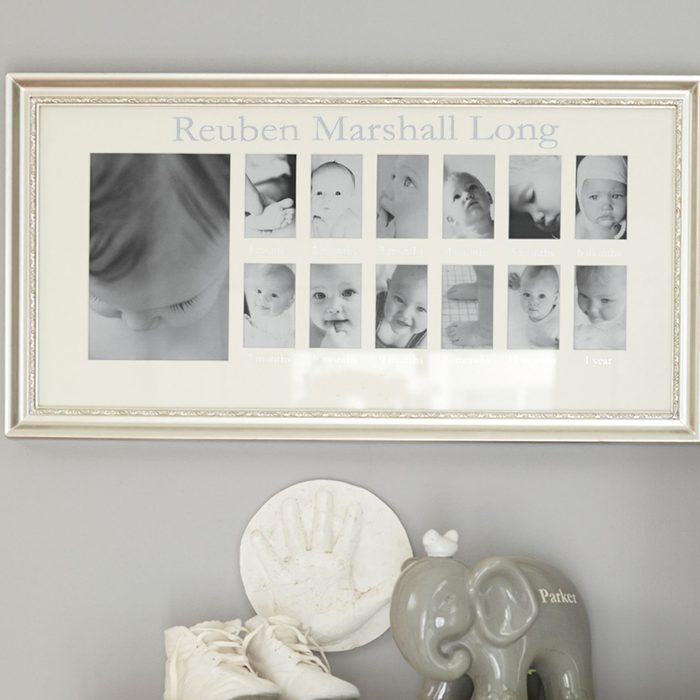 Frame displays baby photos progressing by age; hangs above a plaster handprint, baby shoes, and decorative elephant labeled 