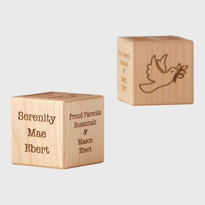 Wooden block displays engraved names and a dove, surrounded by neutral background. Text reads: 