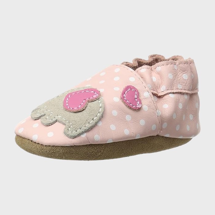 Pink baby shoe features polka dots and heart designs, resting on a plain white background.