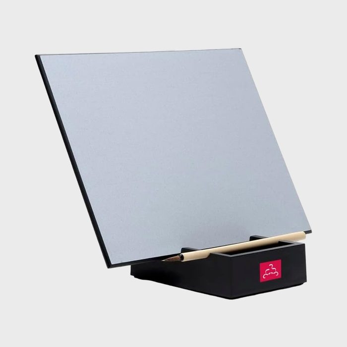 Board displayed at an angle, resting on black stand, holding a wooden brush, with a red logo on a plain white background.