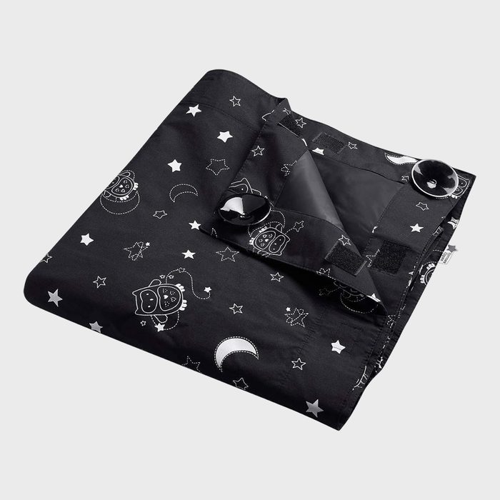 A black fabric displays white stars, moons, and owls; edges are folded with visible suction cups, suggesting temporary attachment ability, set on a plain background.