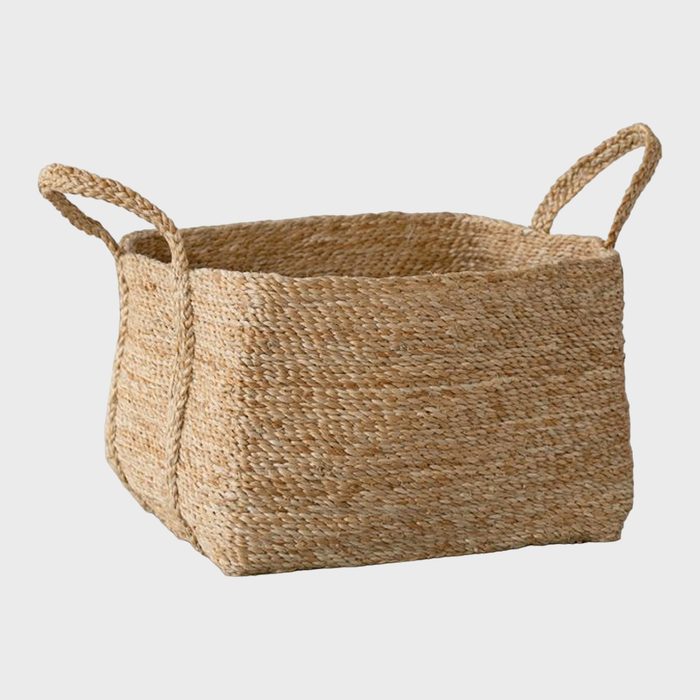 Woven basket with handles, sitting idle, on a plain white background.