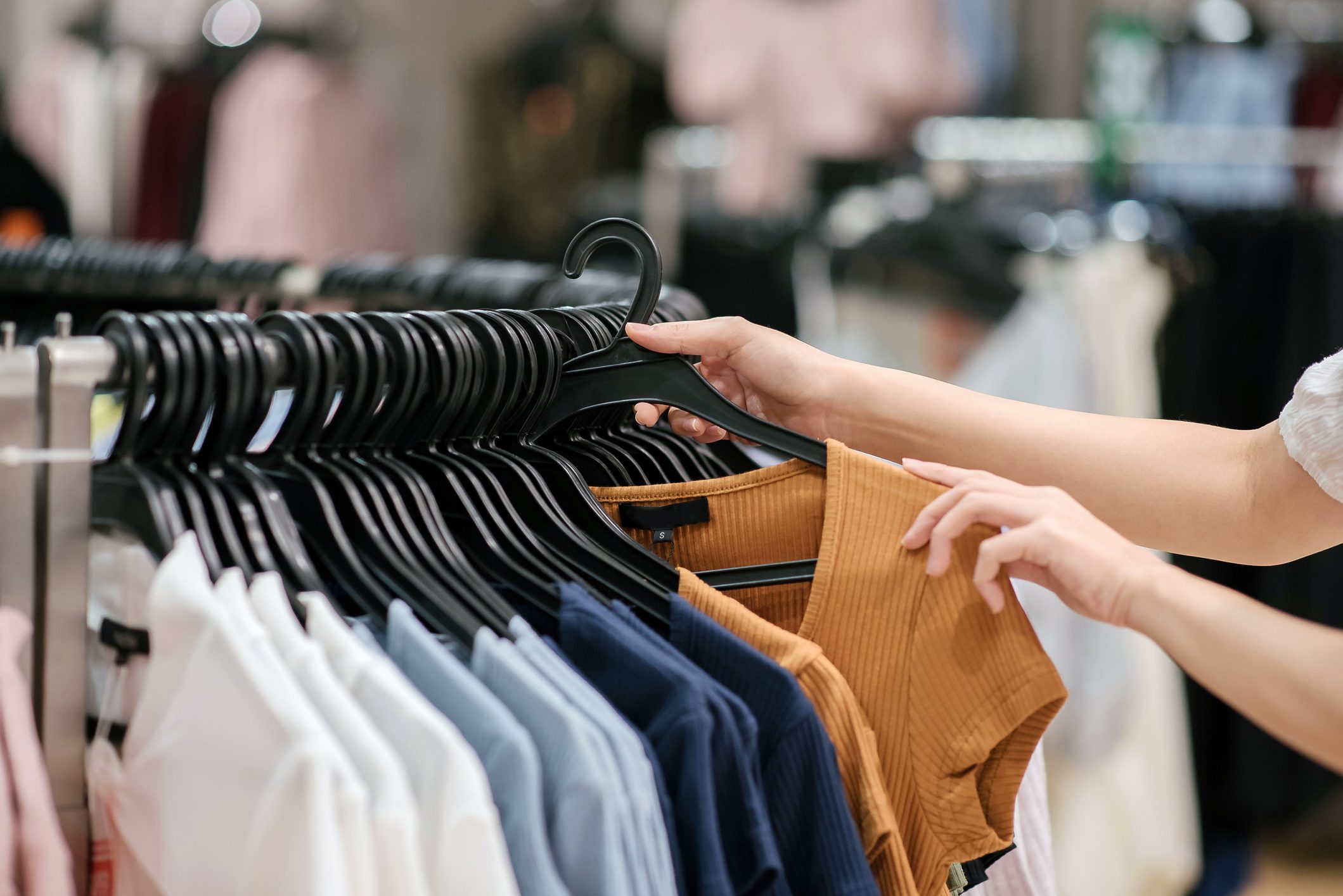 Close-up of asian chinese female hand taking a clothes out at clothing store