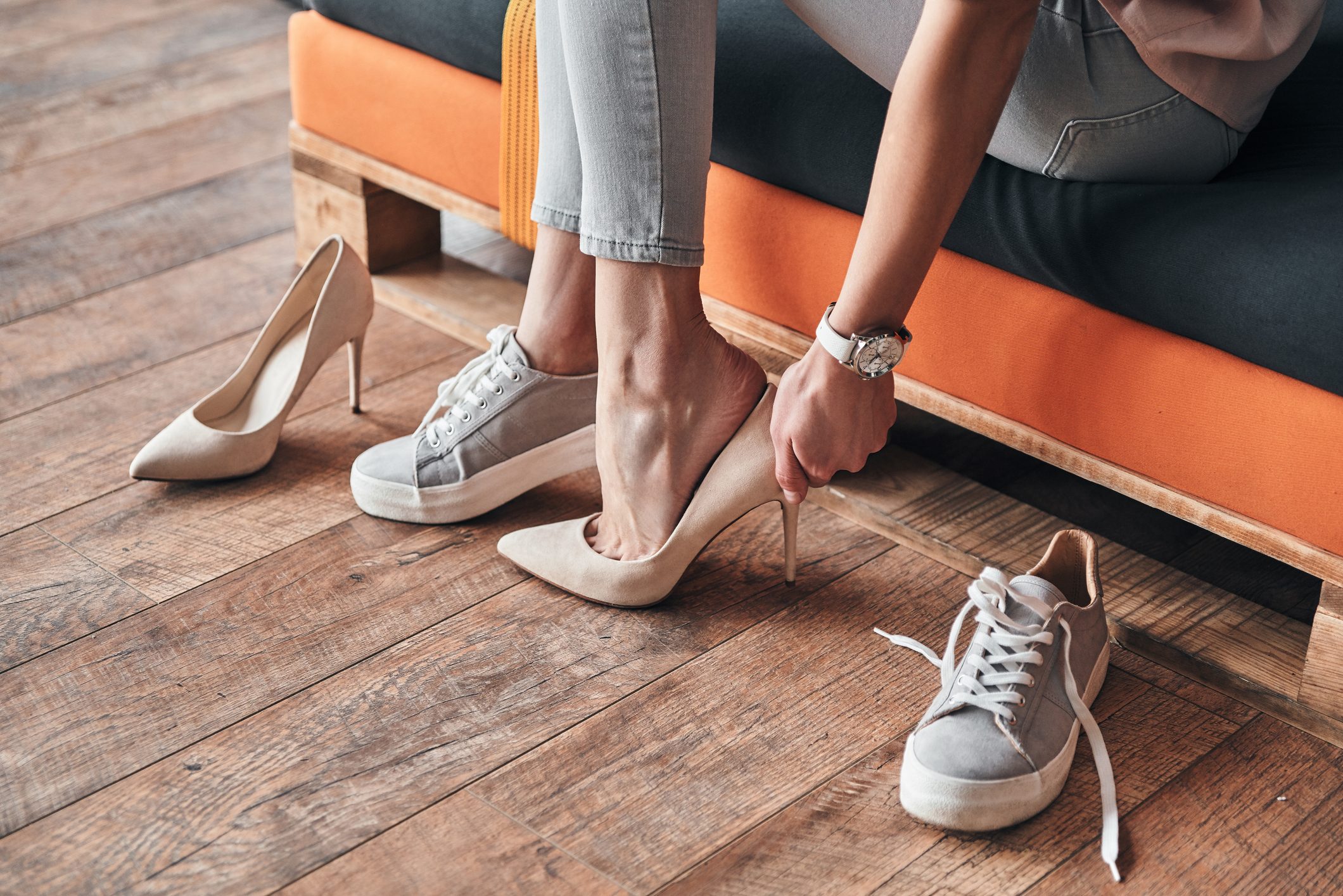 Close up of young woman trying on elegant shoes with high heels while sitting in the shoe store