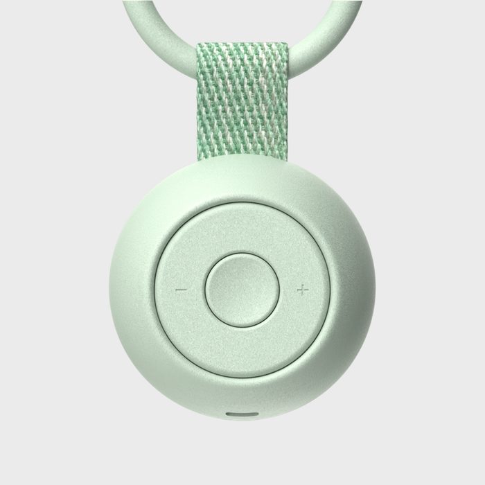 A round, mint-colored remote displays plus and minus buttons, attached to a looped woven strap, set against a plain gray background.