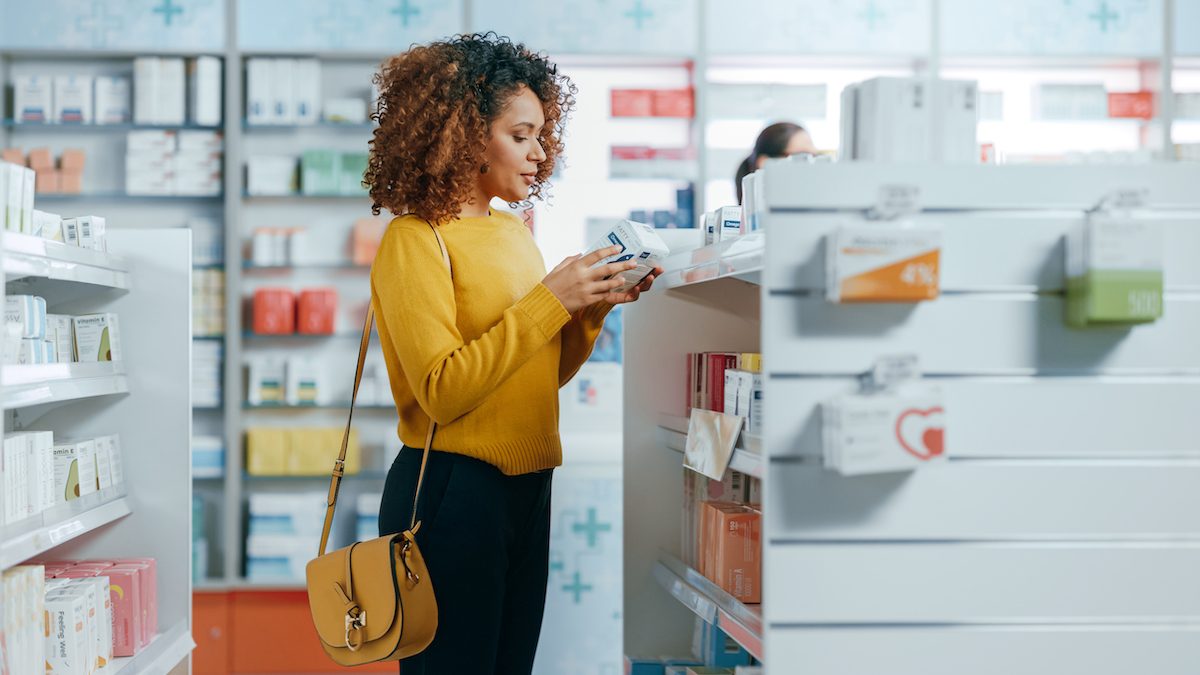 Pharmacy Drugstore: Portrait of a Beautiful Black Young Woman Choosing to Buy Medicine, Drugs, Vitamins. Apothecary Full of Health Care, Pill Bottles, Beauty Cosmetics Products with Modern Design; Shutterstock ID 1999646243; use_print_or_web: -; client_licensee: -; job: -; other: -