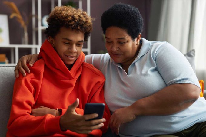 African American Teenage Boy Showing Online Video To His Grandmother