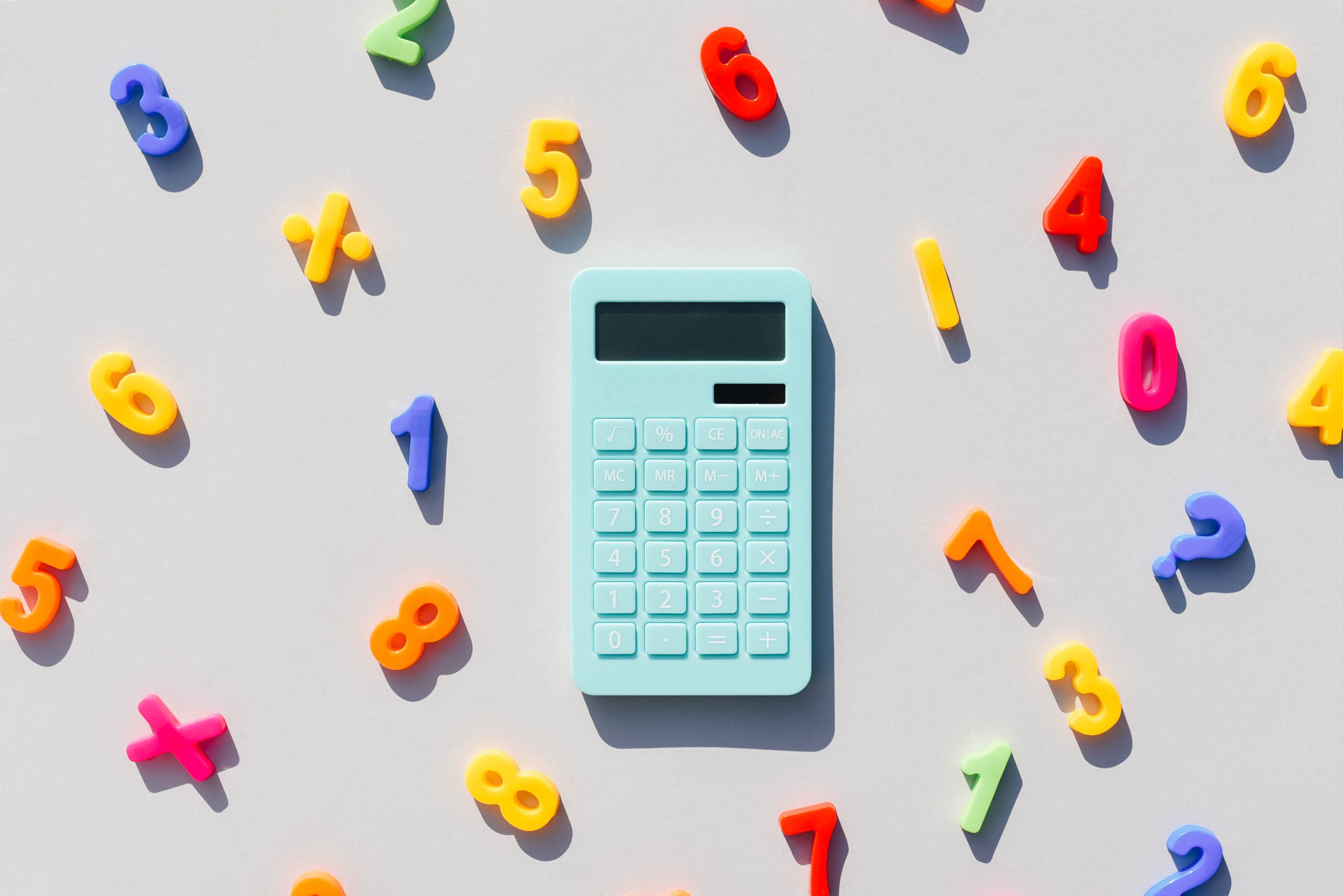 A blue calculator lies among colorful, scattered magnetic numbers on a light background.