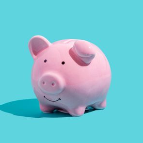 A pink piggy bank sits on a bright turquoise background, casting a shadow to the left.