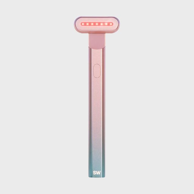 A handheld device emits red light with a sleek design, pink gradient handle, and 