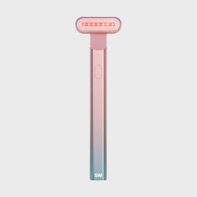 A handheld device emits red light with a sleek design, pink gradient handle, and 