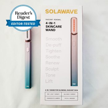 Wand lies next to branded box featuring skincare benefits and therapy types, marked by Reader's Digest as editor-tested, on a neutral background.