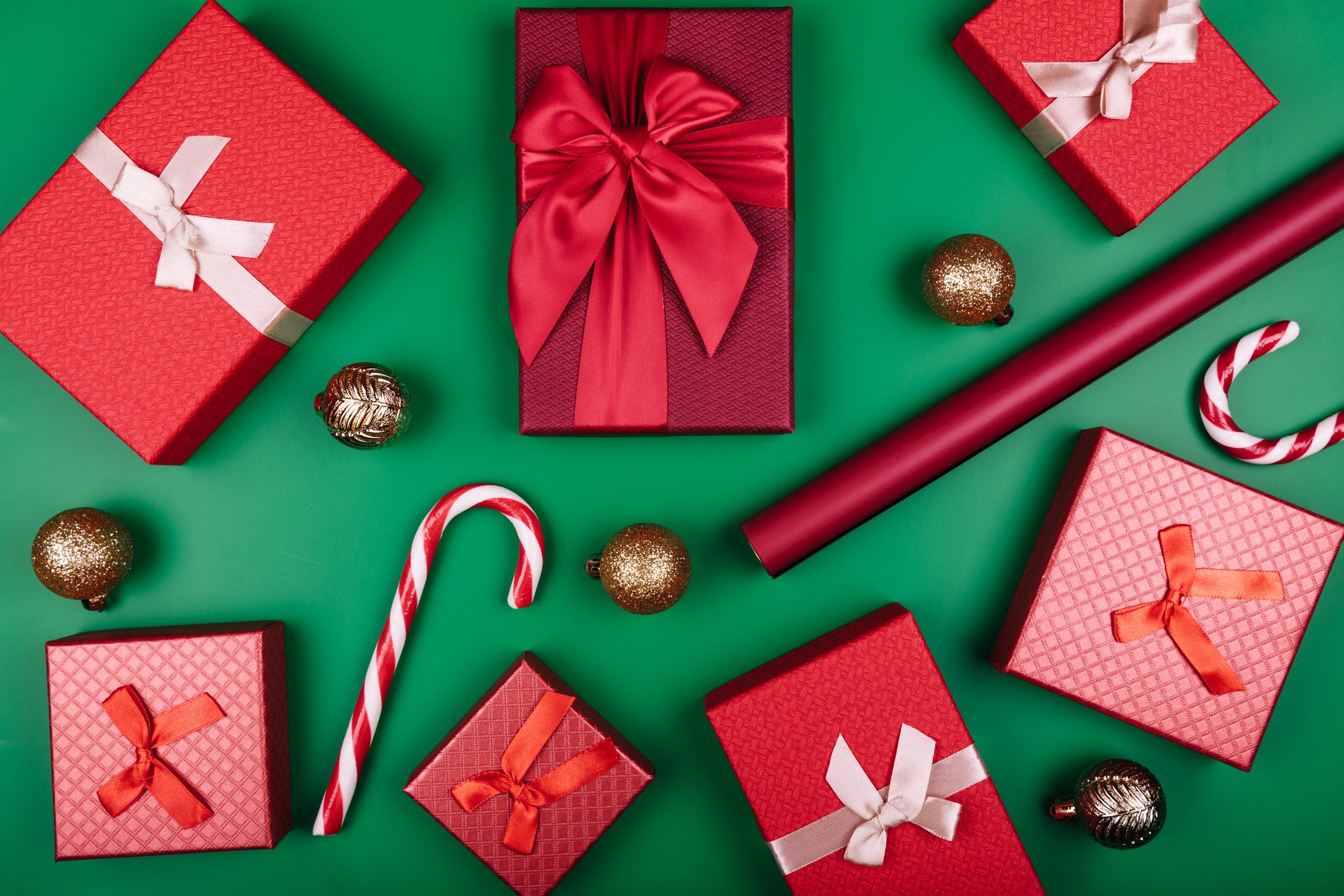 Christmas background with gift boxes, clews of rope, paper's rools and decorations on red. Preparation for holidays. Top view with copy space.