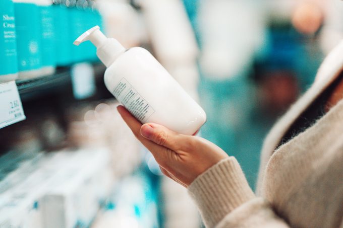 shopping for shampoo at the store and holding shampoo bottle in hand to read the label