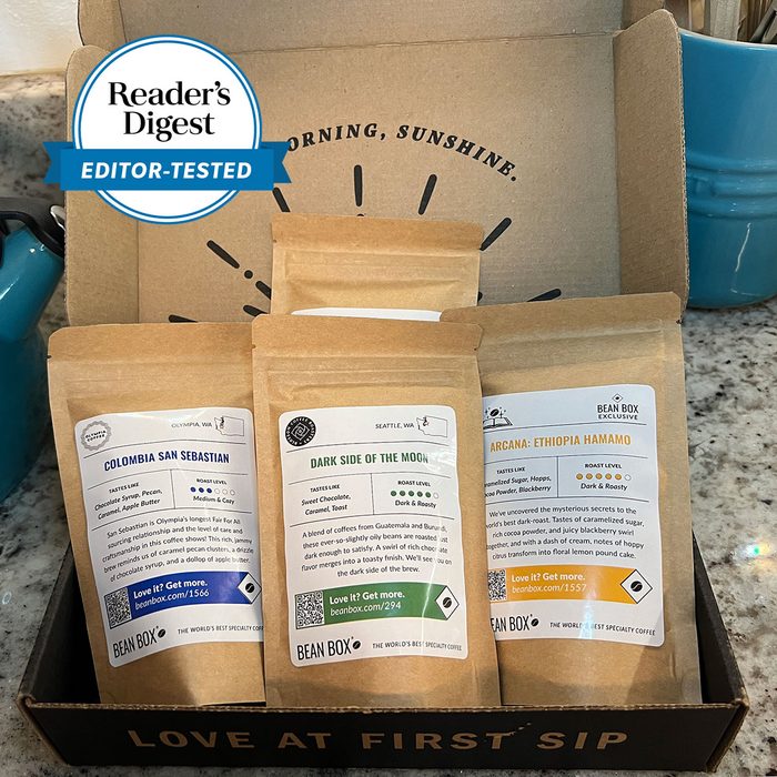 Coffee bags rest in an open cardboard box labeled 