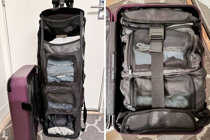 A black collapsible travel shelf holds neatly folded clothes, extending from a purple suitcase in a room with a carpeted floor.