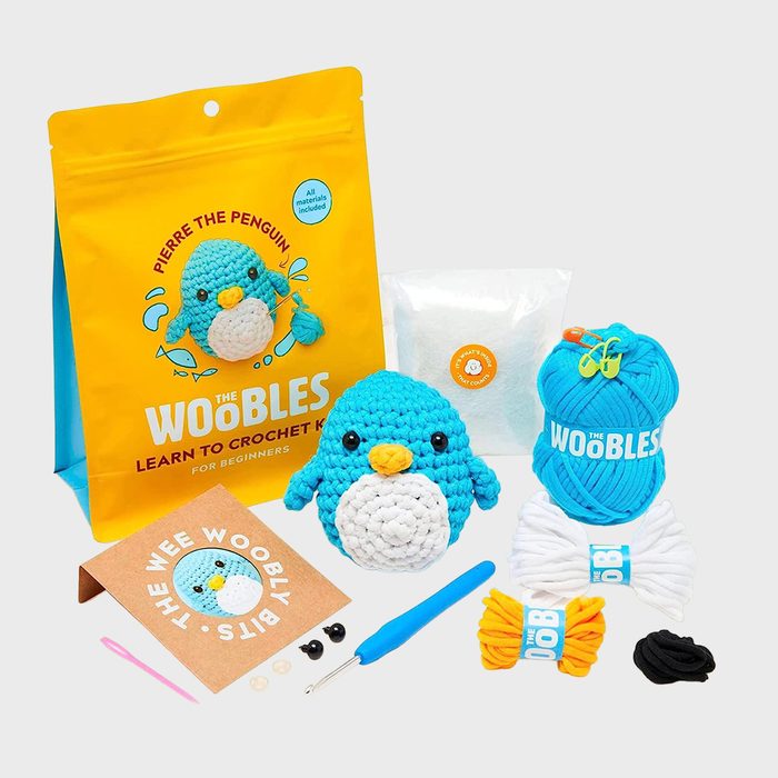Penguin crochet kit includes yarn, crochet hook, and stuffed penguin. Packaged with instructional materials. Perfect for beginners learning to crochet in a vibrant setting.