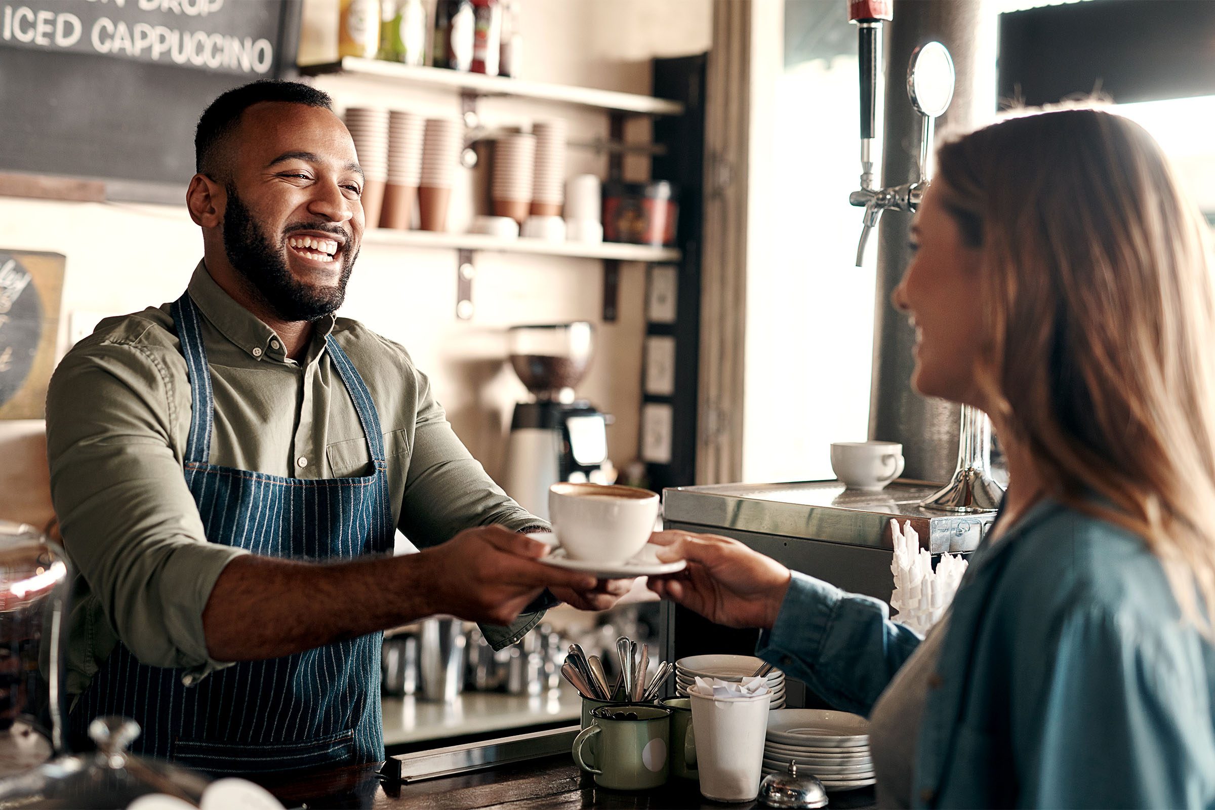Smiling barista handing over coffee to customer