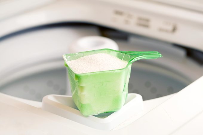 borax cup resting on the edge of a top loading washing machine