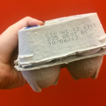 A hand holds a small egg carton against a red background. Text reads: "Sell by 10/06/17."
