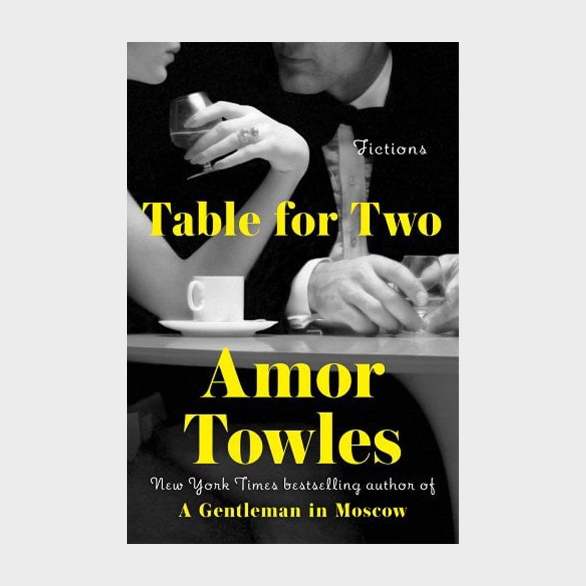 Cover shows a man and woman holding drinks at a table. Text reads: "Table for Two, Amor Towles, Fictions."