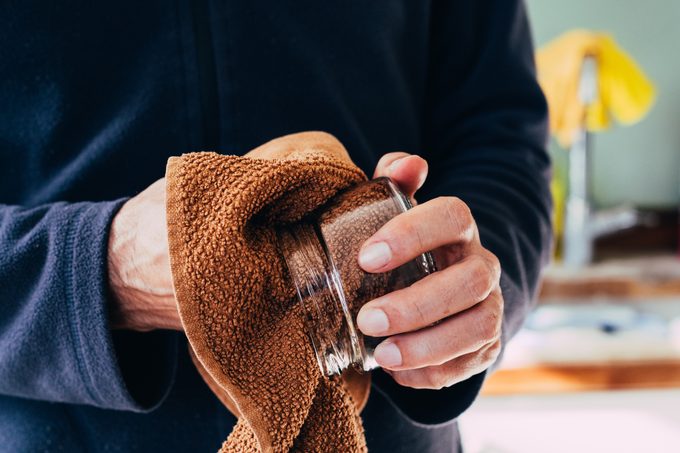 A man wiping washed dishes with towel