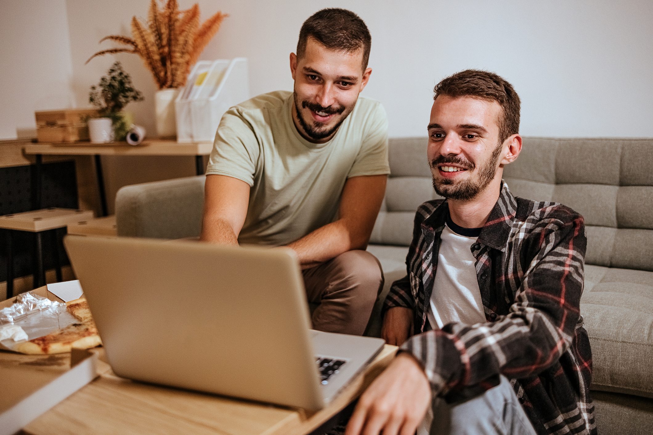 Young gay coupleYoung gay couple sitting on sofa at home. Using a laptop and watching a movie