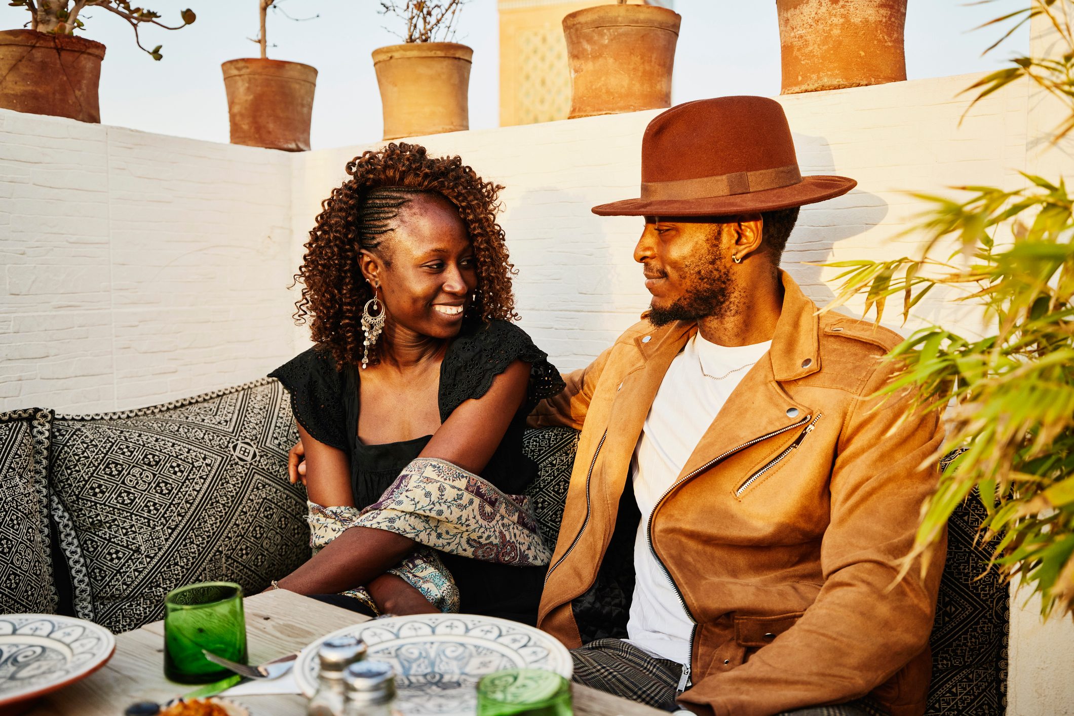 Medium shot of smiling couple dining at rooftop restaurant in Marrakech