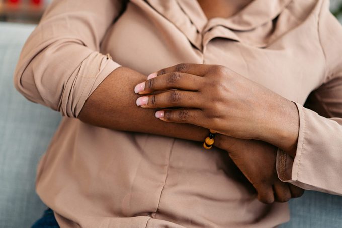 Young Woman Scratching Her Skin At Home