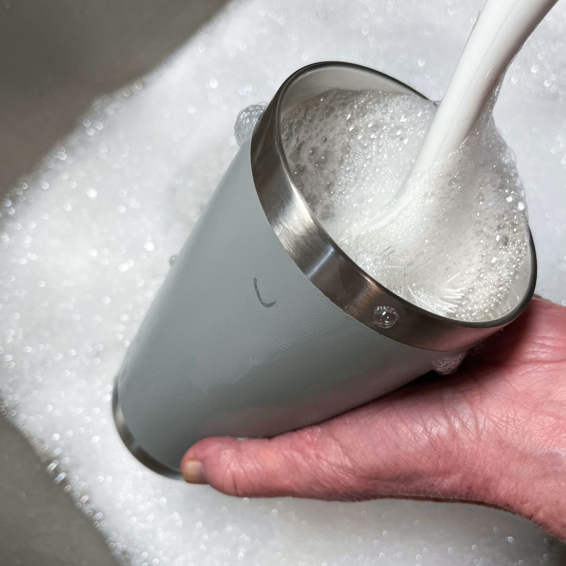 A person washing his water bottle in a sink