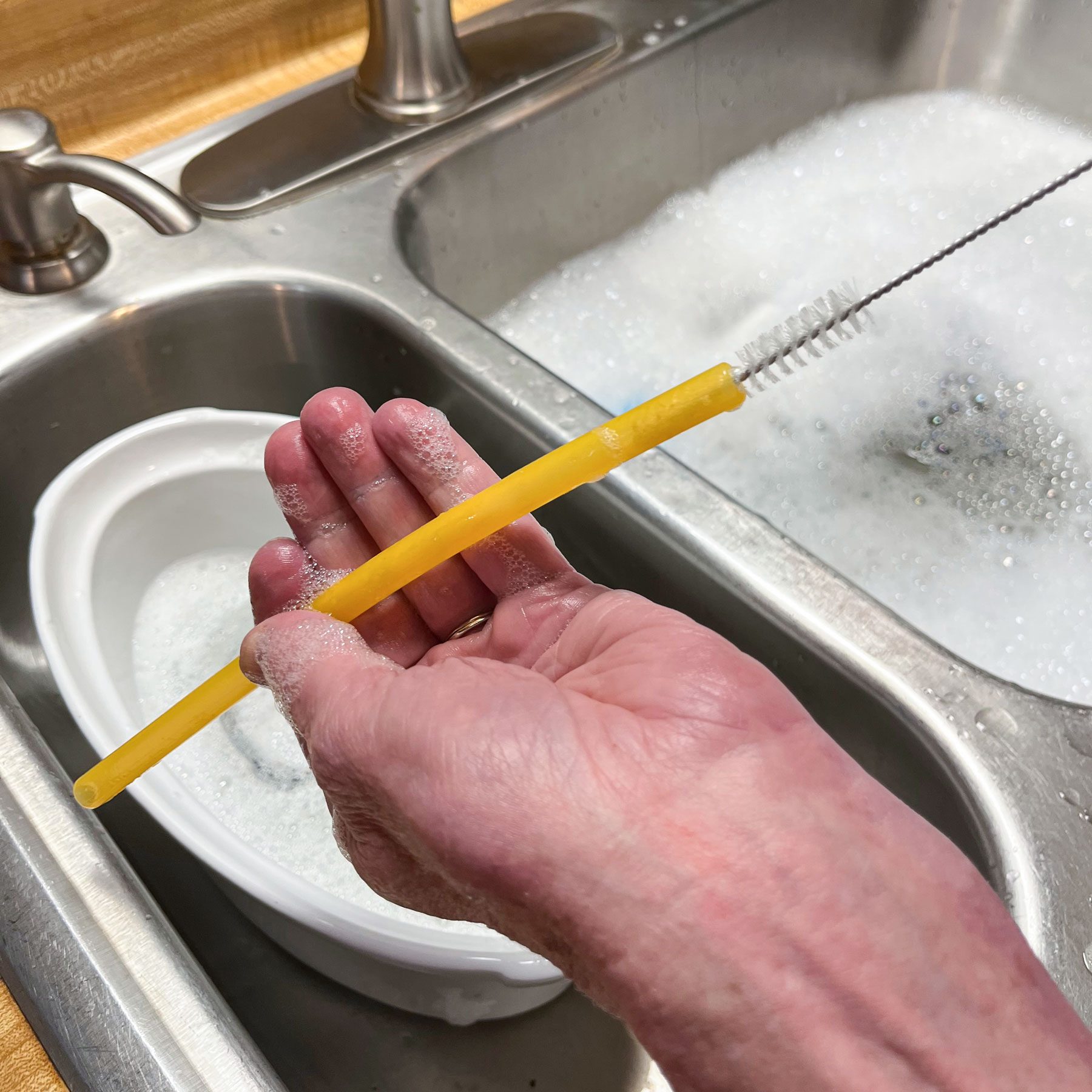 Cleaning the yellow straw through a mall brush