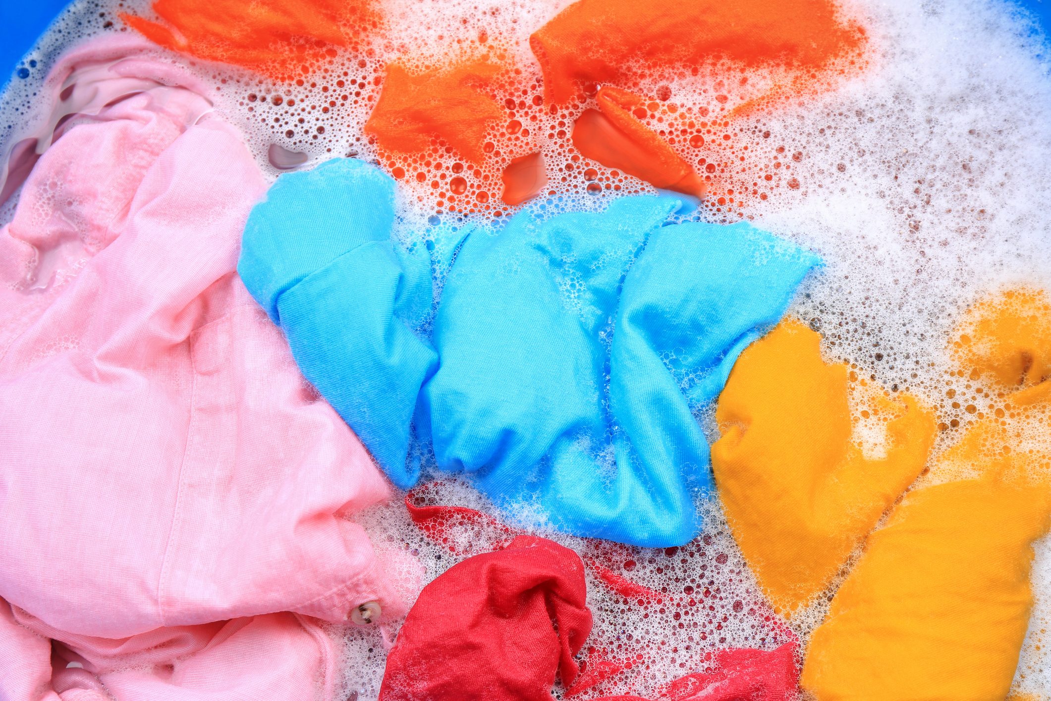 Colorful clothes in suds, top view. Hand washing laundry