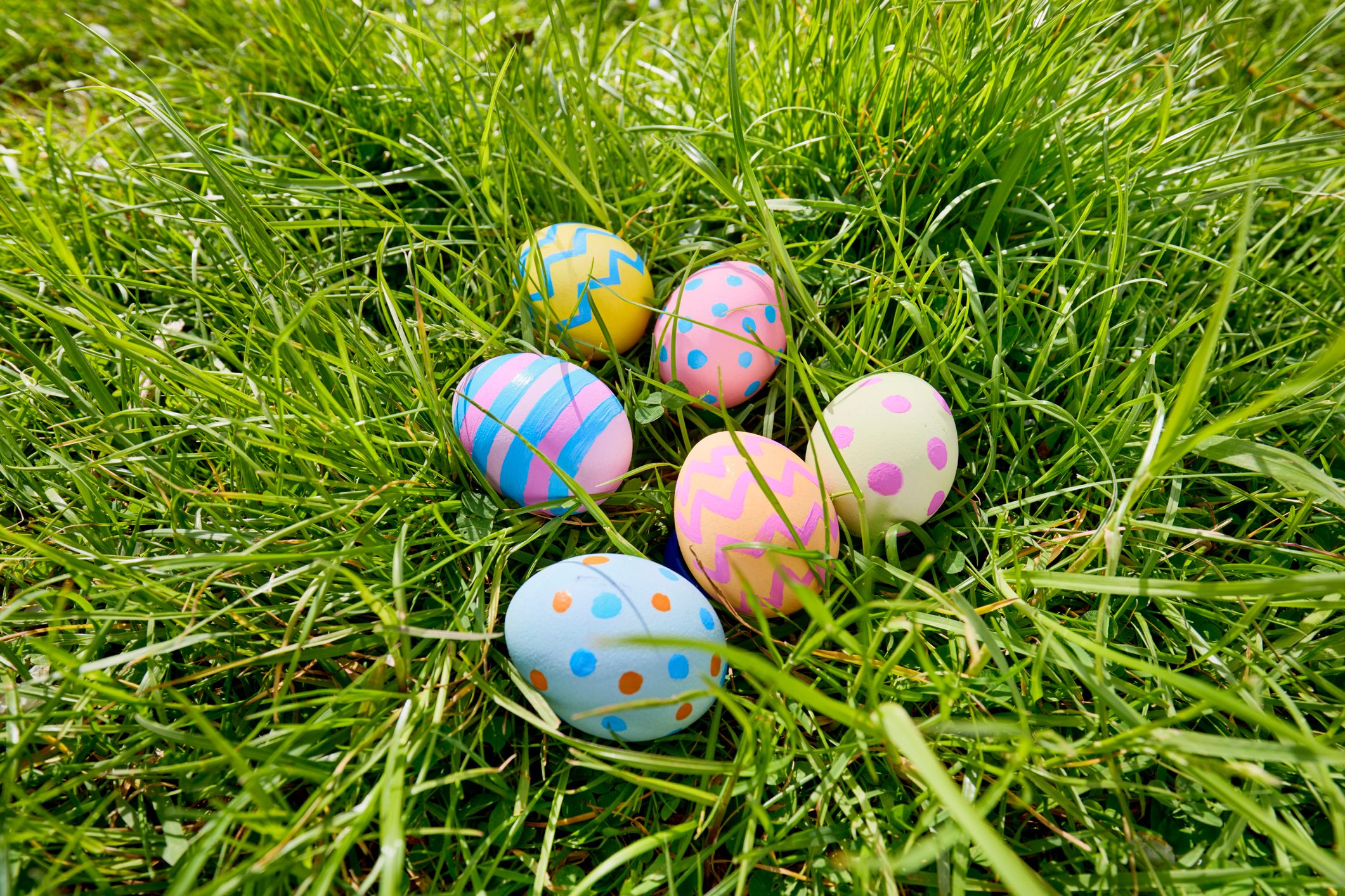 Colorful, patterned eggs rest nestled in vibrant green grass, creating a festive and playful outdoor scene.