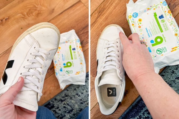 A Person Cleaning White Leather Shoes with Baby Wipes , Wooden Background.