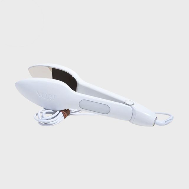 White hair straightener lies on a light surface, with 