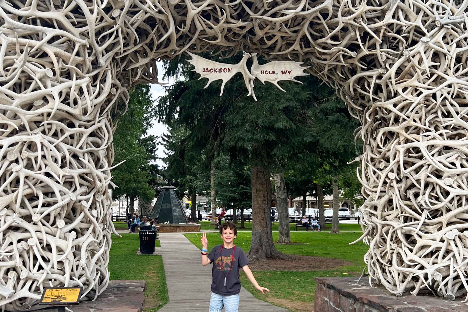 A kid posing for a photo at antler arches
