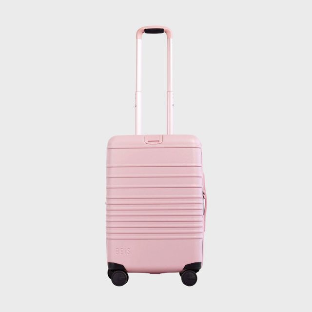Pink suitcase stands upright, handle extended, on a plain white background.