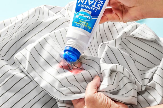 Hand applying enzymatic stain remover to blood stain on sheets