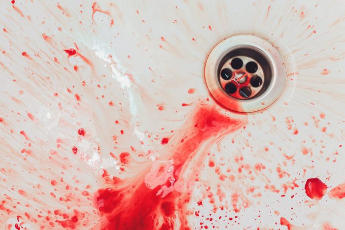 Fresh red blood splat on white porcelain with specks from the impact. Copy space area for horror themed concepts and ideas.