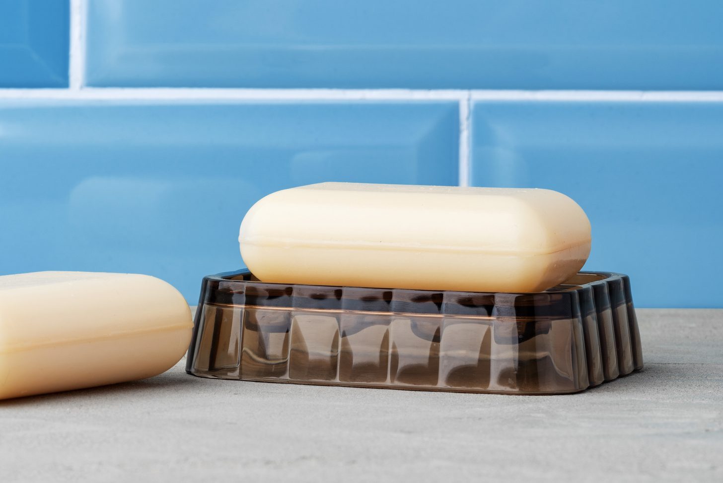 White soap bar on plastic dish in blue bathroom
