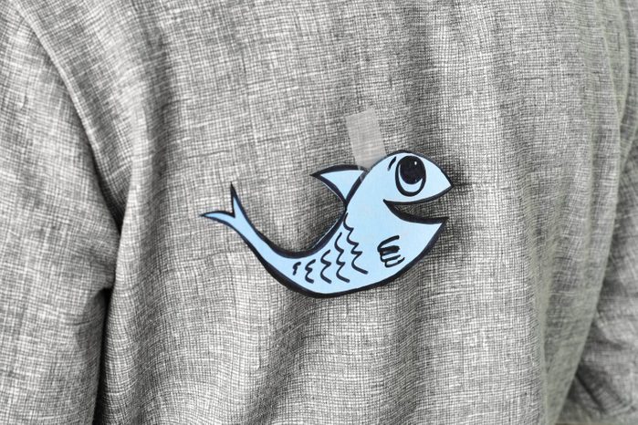 young man with a paper fish attached to his back