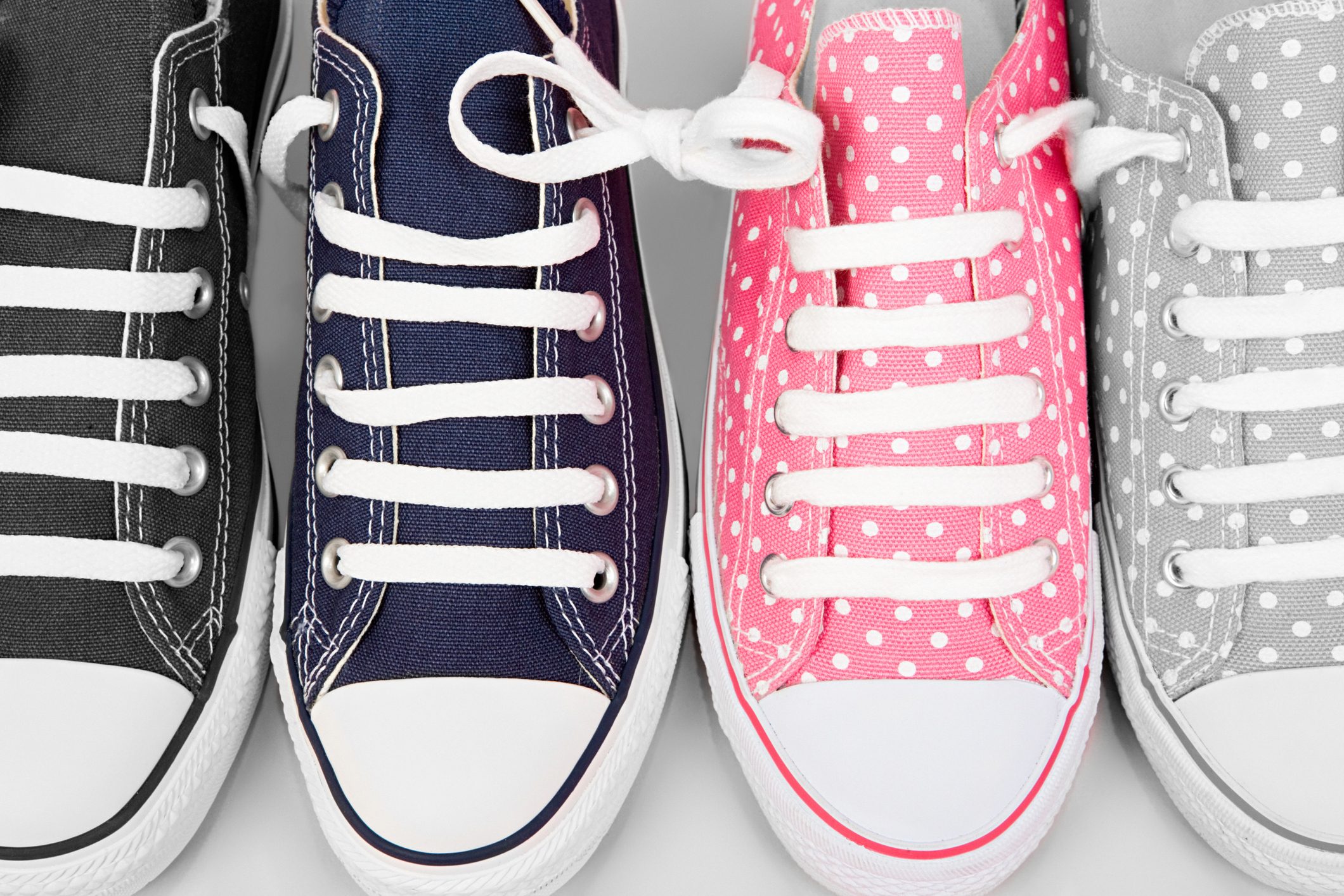 Sneakers aligned in a row display colorful fabrics with polka dot patterns, featuring white laces on a flat surface.
