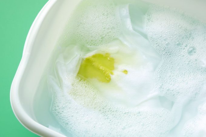 Garment with the oil-based stain soaking in a tub of sudsy water