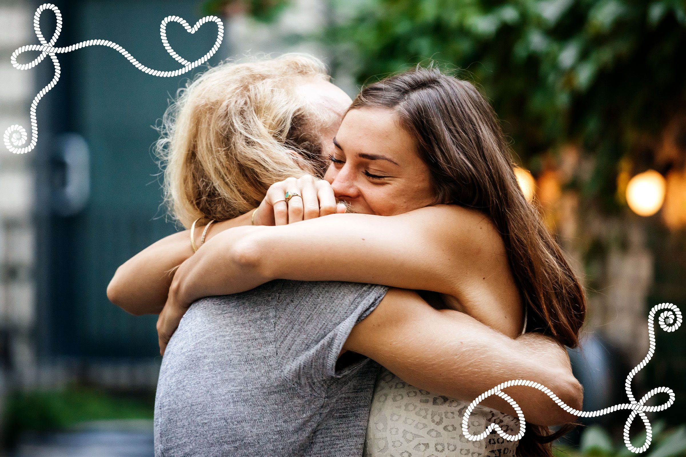 Two people embrace warmly outdoors, surrounded by greenery. White spirals and hearts decorate the image, suggesting love and connection.