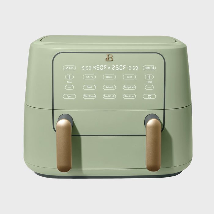 Green air fryer with control panel, featuring buttons for cooking modes and settings. Two gold handles below, set against a plain background.